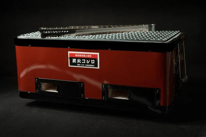 Konro grill Komon BBQ avec plaque teppan en fonte rouge, corps en diatomite pour cuisson au binchotan, vue trois-quarts avec accessoires.