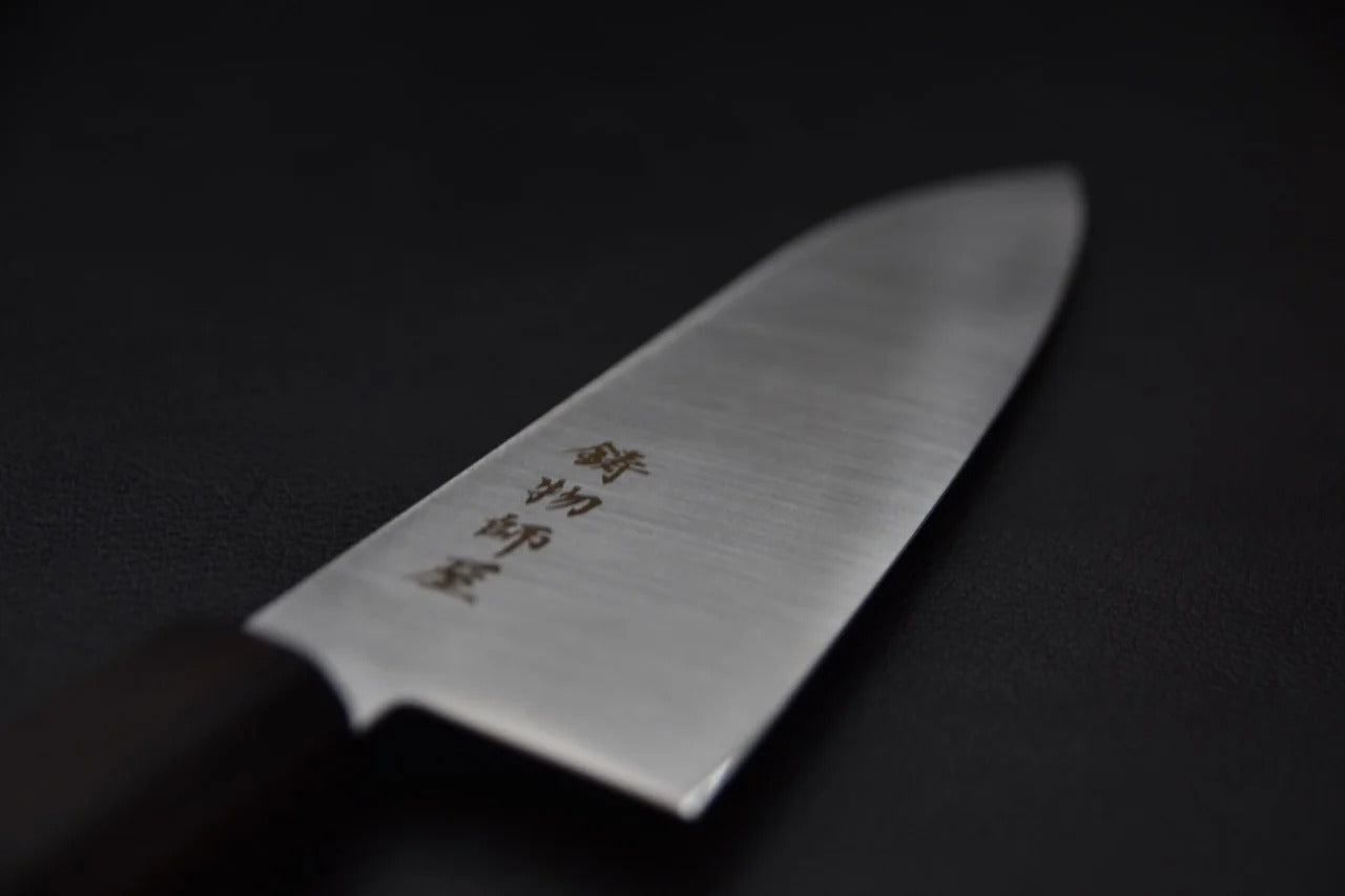 Couteau japonais santoku Hitohira Imojiya TH de 180 mm, acier inoxydable et manche en bois d'ébène, vue d'angle détaillée du corps de la lame.