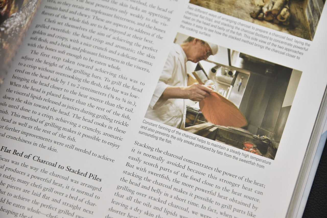 Chef japonais utilisant un éventail pour contrôler la chaleur lors de la cuisson sur charbon, extrait du livre Yakiba