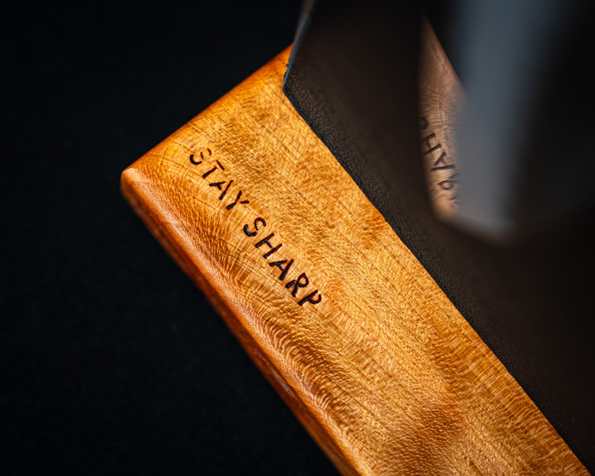 Zoom sur la base en merisier d’un support magnétique Stay Sharp, avec gravure au laser visible et couteau japonais inséré.