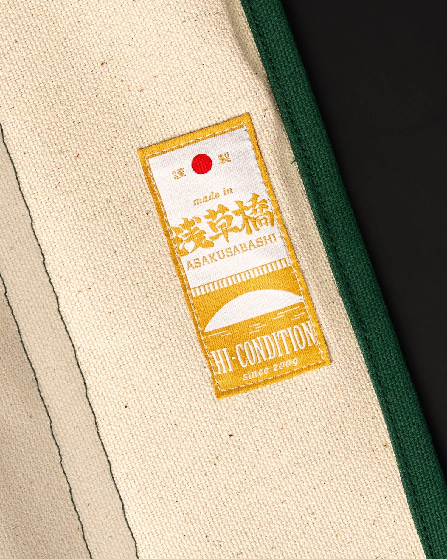 Détail de la toile hanpu verte, de l’œillet métallique et du cordon du rouleau pour couteaux japonais.
