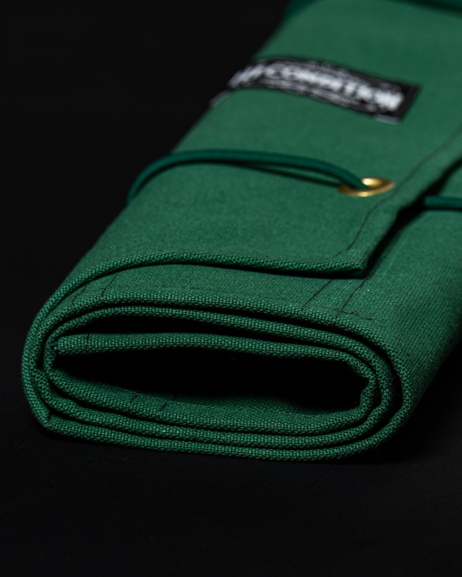 Détail de l’étiquette intérieure Asakusabashi cousue sur le rouleau vert pour couteaux japonais.