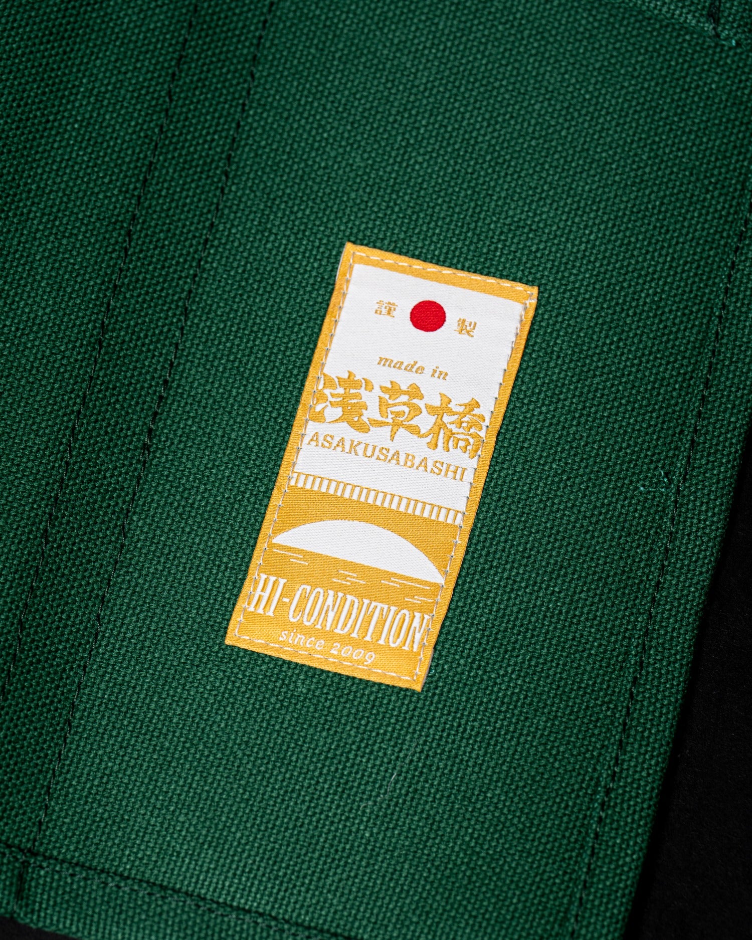 Détail de l’étiquette noire HI-CONDITION, de la toile verte et de l’œillet métallique du rouleau.