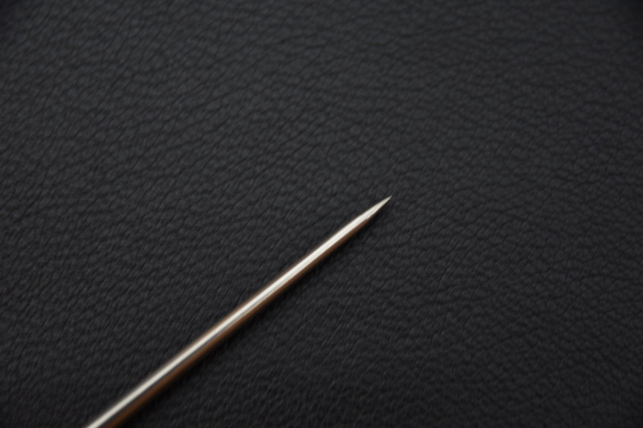 Pointe fine du pic à anguille Hitohira Meuchi en acier inoxydable sur fond texturé.