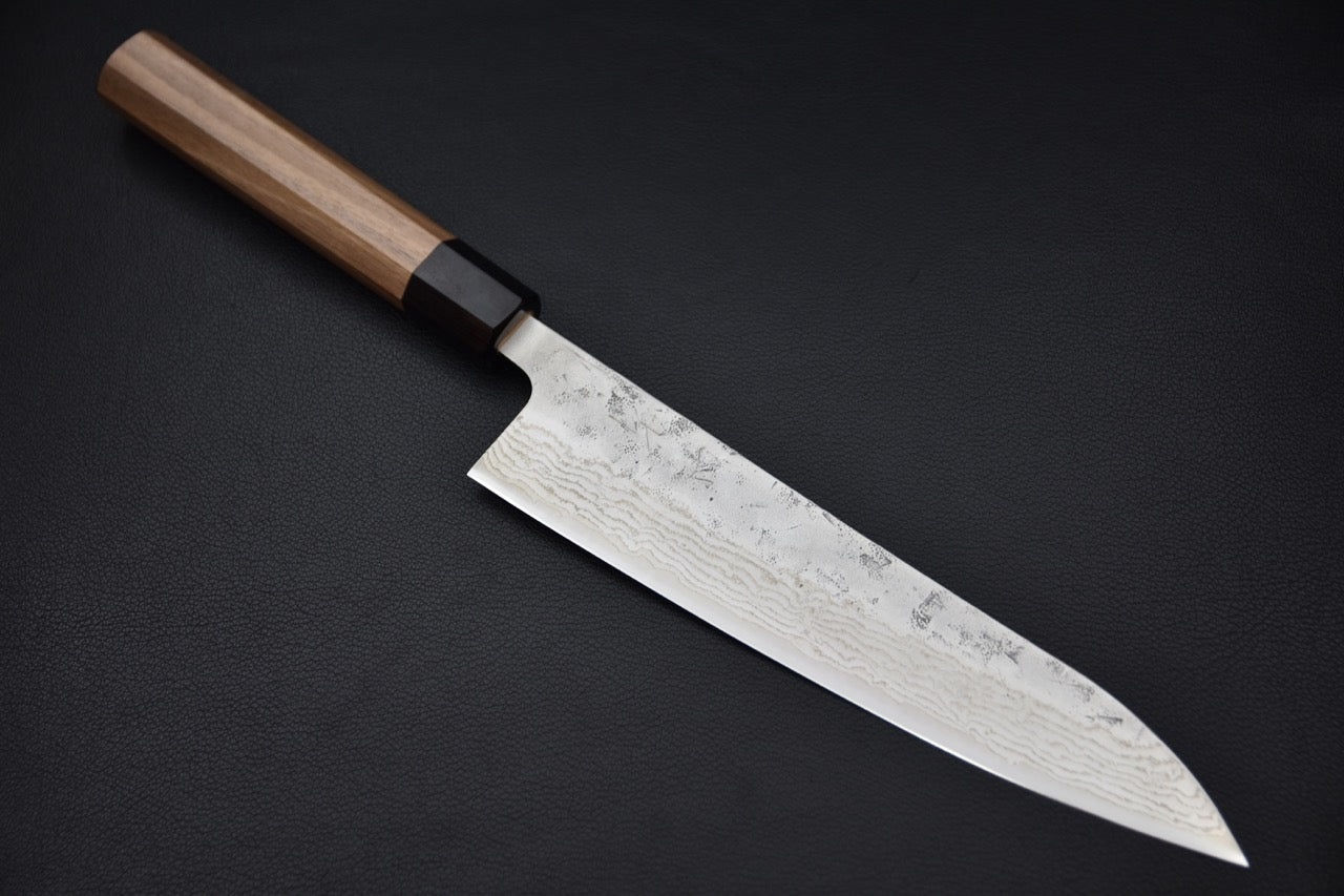 Vue complète du couteau Hitohira Futana Gyuto 210mm posé sur fond noir, montrant sa lame damassée et son manche en noyer.