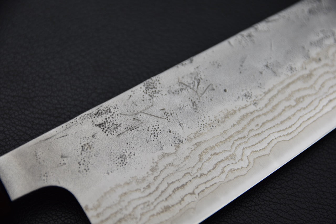 Gros plan sur le motif damassé de l'acier, révélant les couches repliées