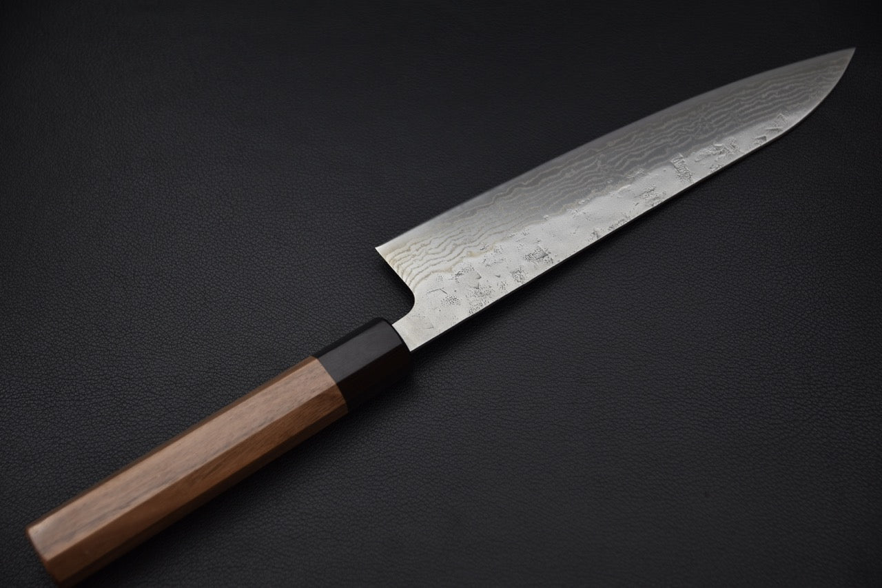 Détail rapproché de la partie supérieure de la lame montrant le motif damas complexe et les textures uniques.