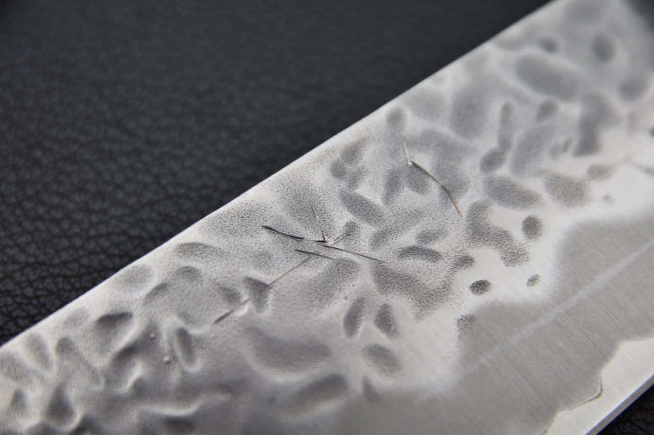 Détail de texture et rayures superficielles sur la surface martelée de la lame