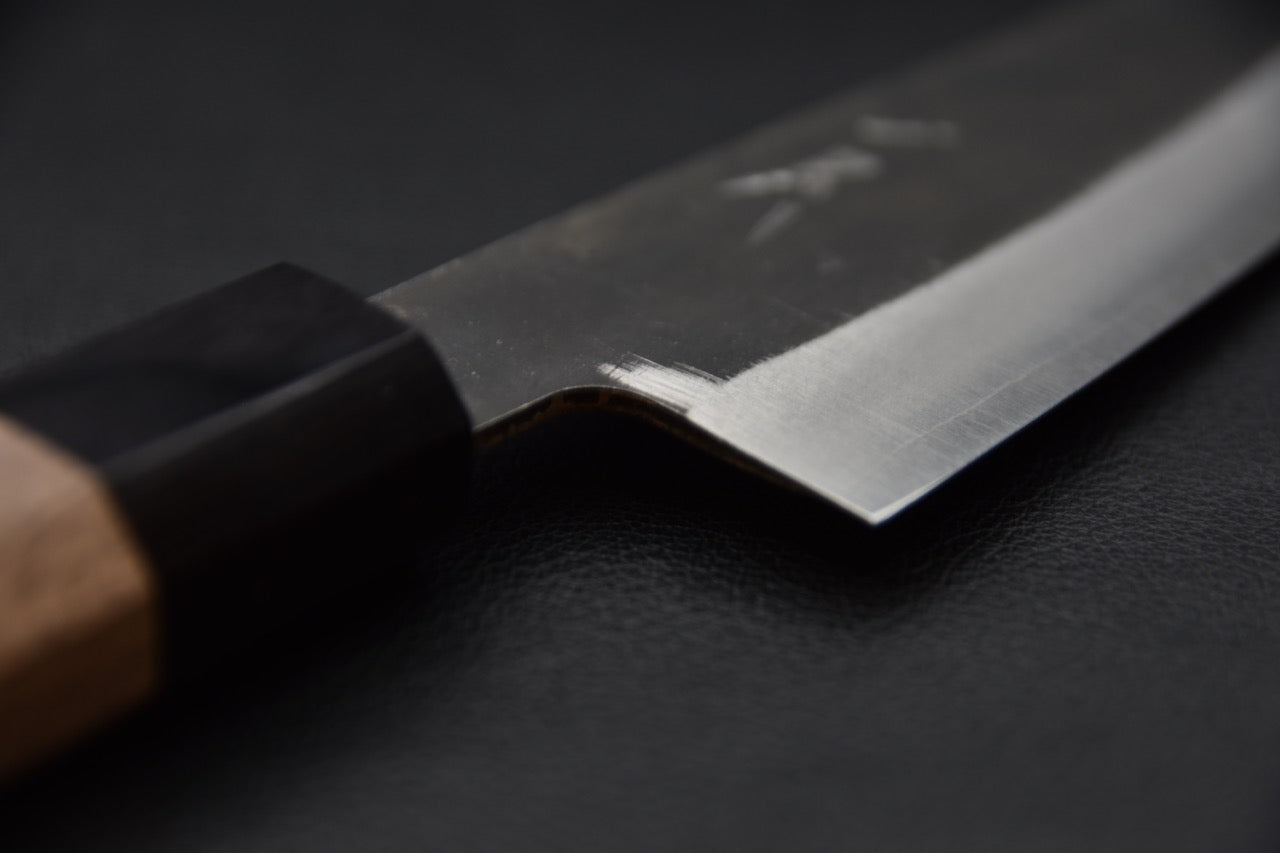 Vue de dos montrant la finesse du biseau d’un couteau japonais japonais en Aogami Super.