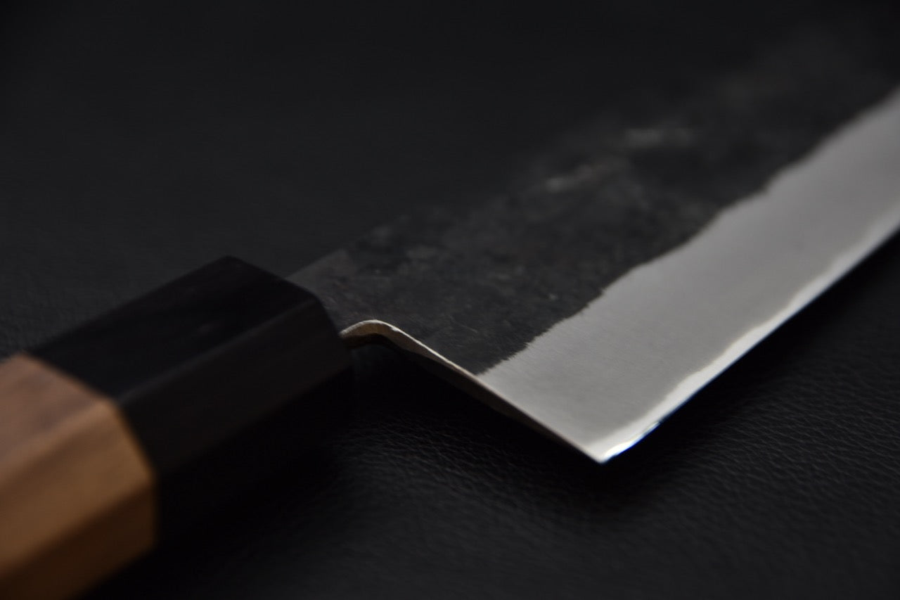 Détail de la base de la lame et du manche du couteau japonais Bunka Hitohira Harima, finition kurouchi.