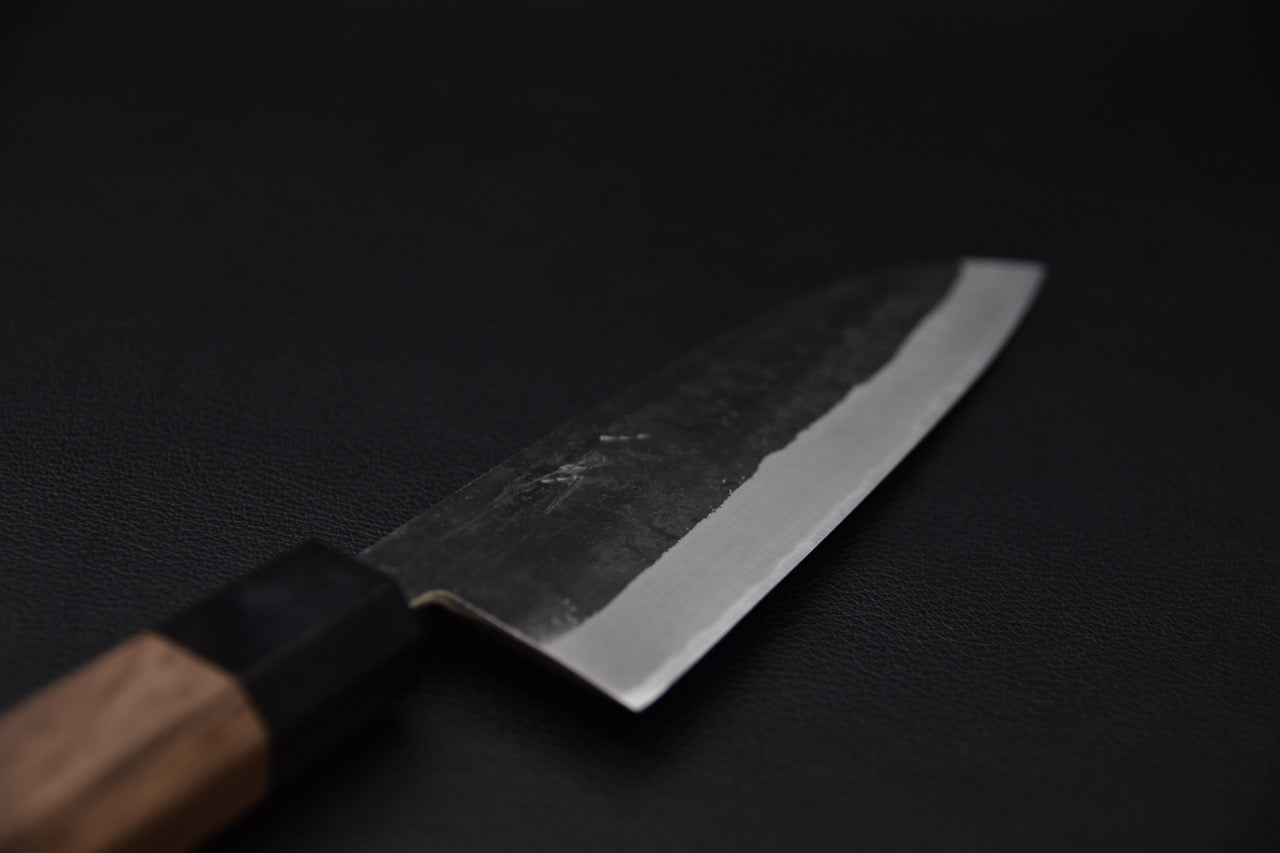 Couteau japonais Santoku Hitohira Harima Blue #2 Kurouchi, gros plan sur la lame et sa finition brute de forge.