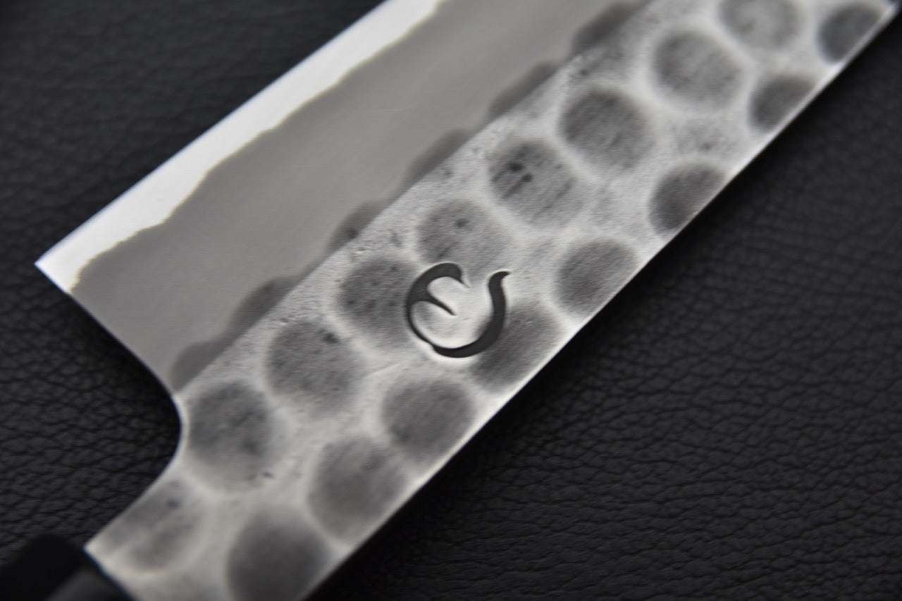 Focus sur le logo en forme de goutte embossé dans la finition Tsuchime.