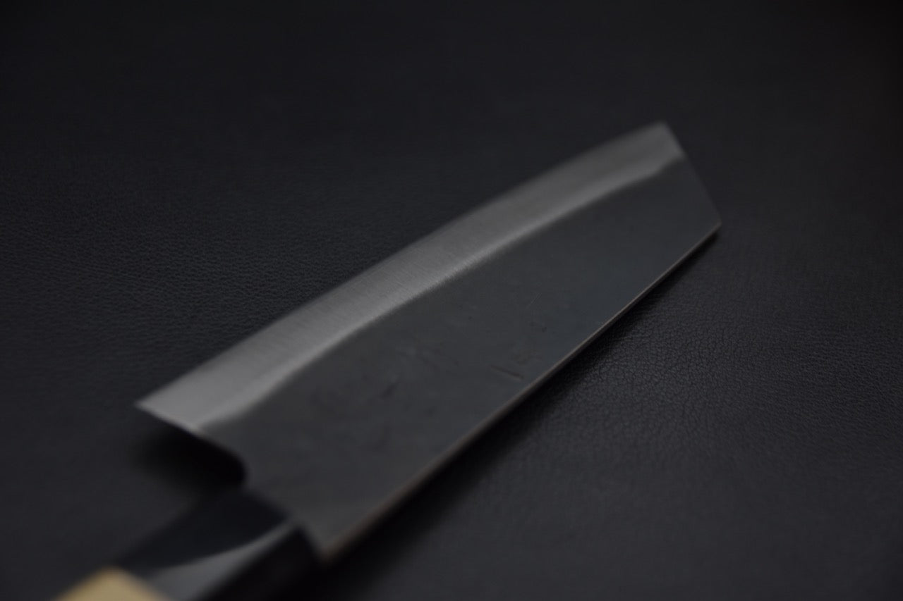 Couteau japonais Bunka vu de biais avec sa finition kurouchi et tranchant brillant.