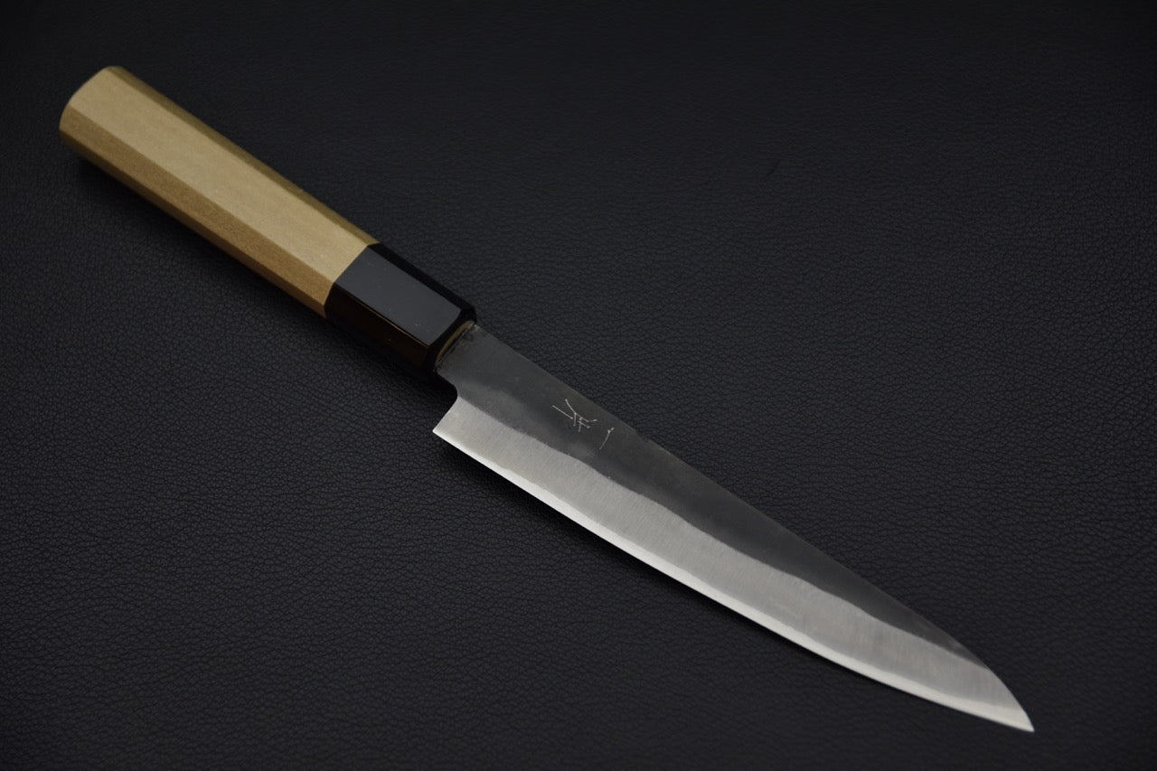 Couteau japonais Petty 150mm avec lame en Aogami #1 et finition kurouchi sur fond noir.