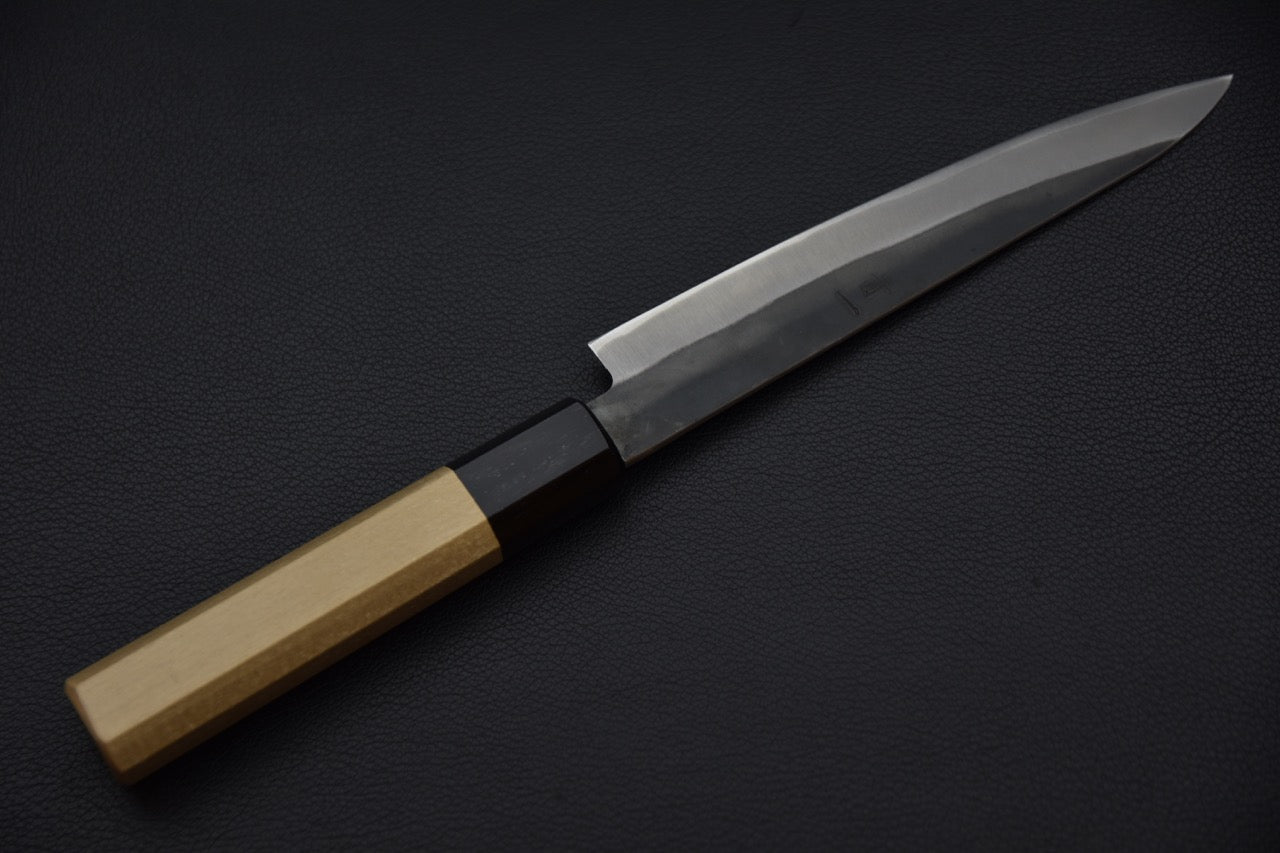 Détail du biseau d’un couteau japonais Petty avec gravure visible sur la lame.