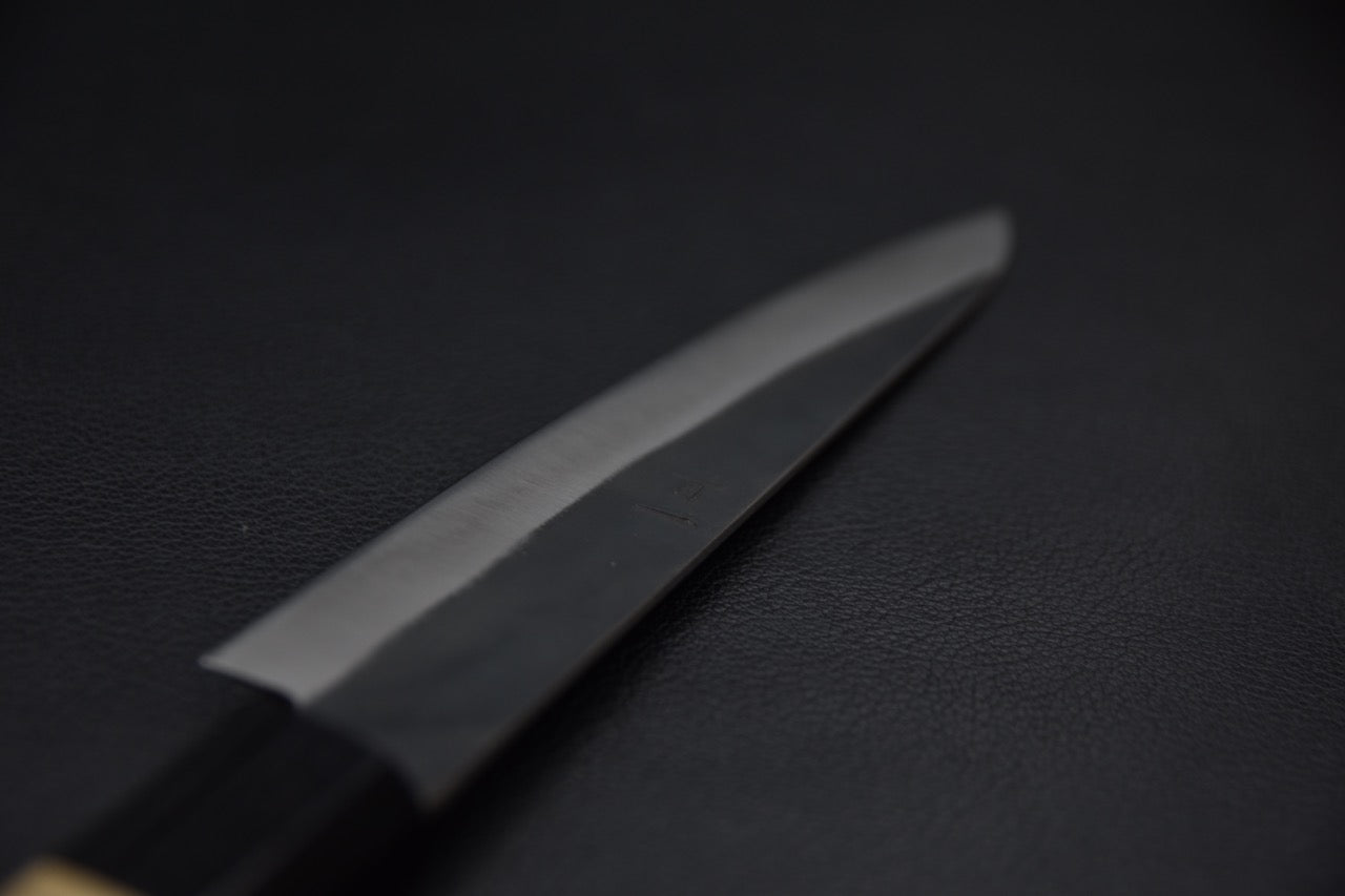 Pointe affûtée d’un couteau japonais Petty vue de face, montrant la finesse de la lame.