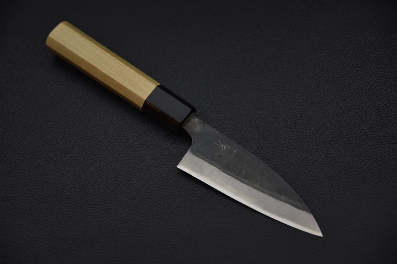 Couteau japonais utilitaire avec lame en acier Aogami #1 et finition kurouchi sur fond noir.