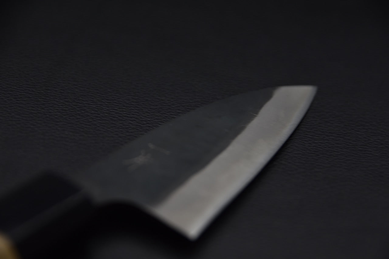 Gros plan sur la lame du couteau japonais montrant le tranchant poli et le biseau symétrique.