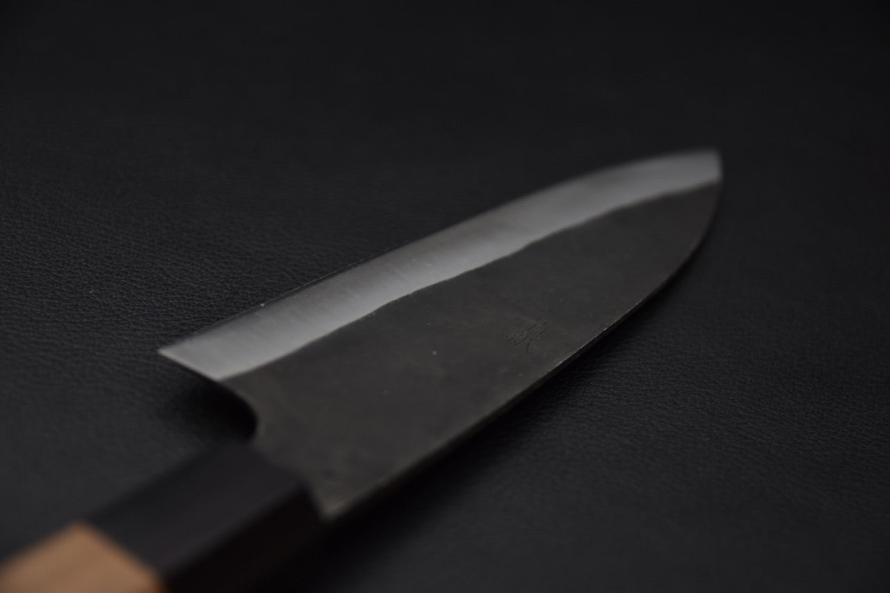 Couteau japonais artisanal, finition kurouchi rustique avec contraste lame tranchante.