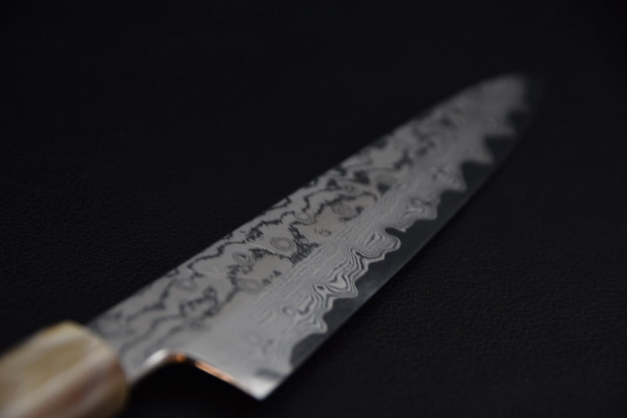 Couteau japonais gyuhiki VG-10, détail de la lame damassée près de la pointe en angle rapproché.