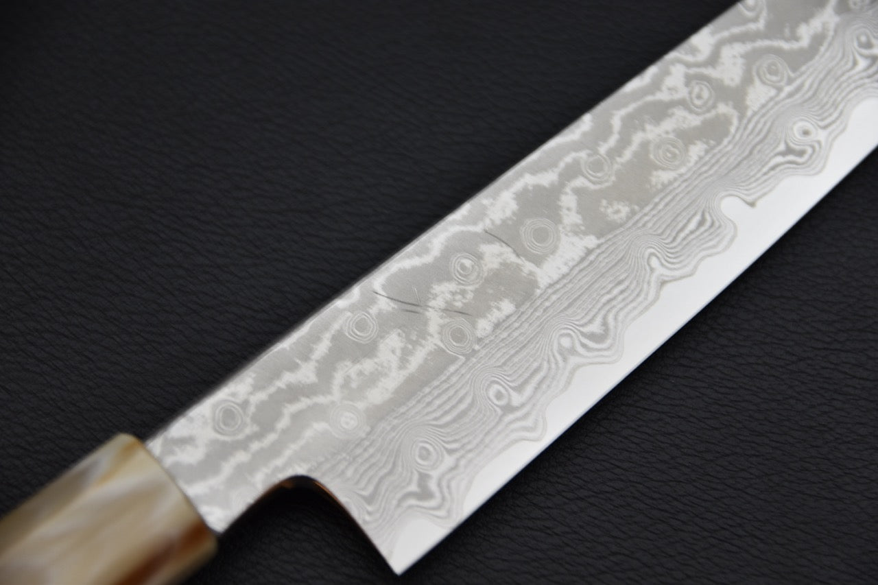 Couteau japonais gyuhiki damassé, gros plan sur le motif de la lame près du talon et du tranchant.