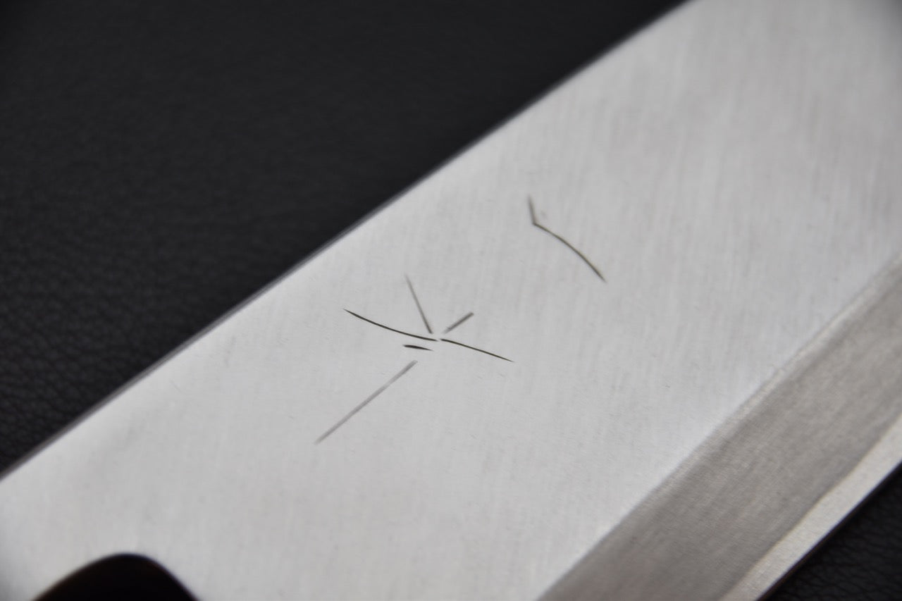 Gravure minimaliste sur la face de la lame, typique des couteaux Kikuchiyo Manzo.