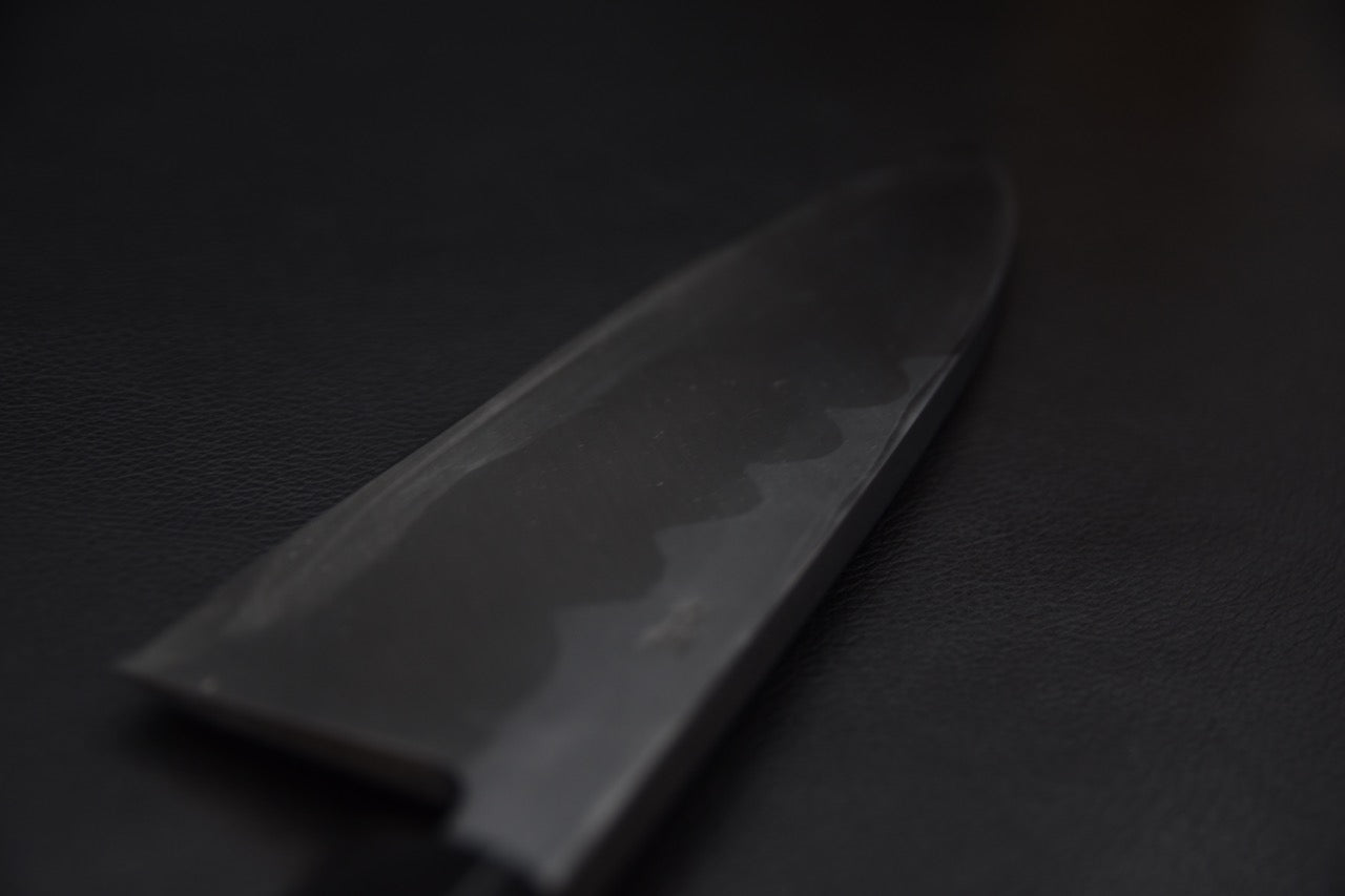 Lame polie du Deba avec reflet ondulé de la trempe sur fond sombre.