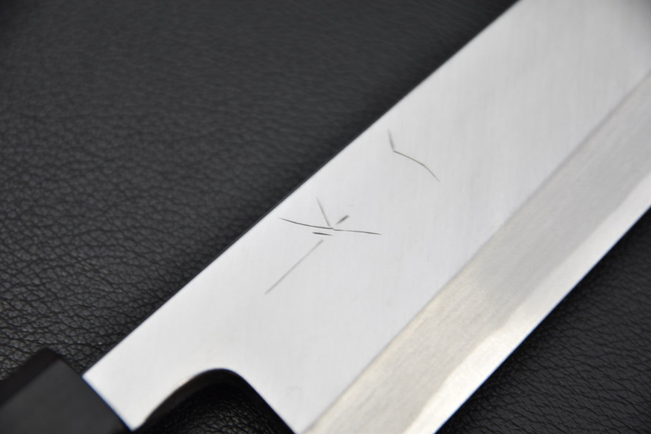 Gros plan sur la surface de la lame et la ligne de trempe du couteau japonais Mioroshi Deba