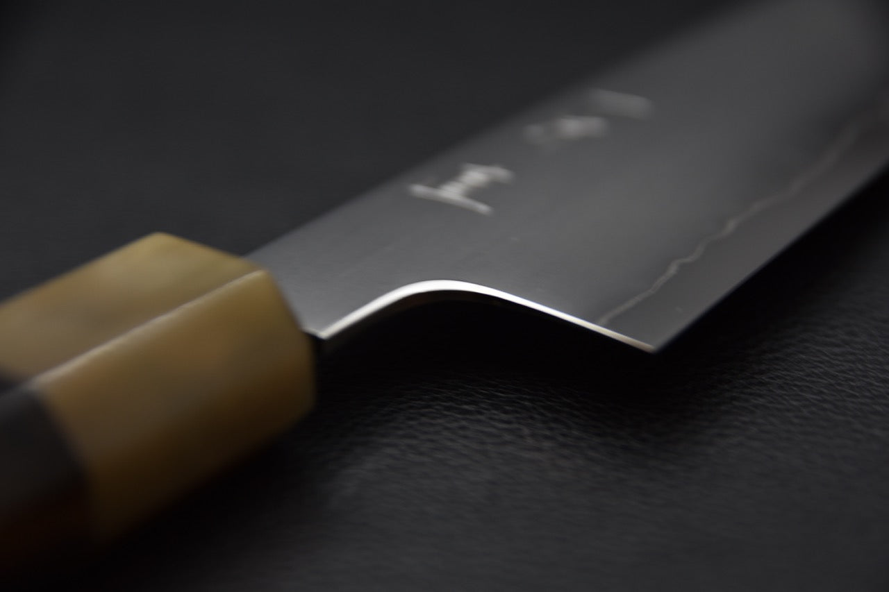 Vue rapprochée du talon du couteau mettant en valeur les finitions.