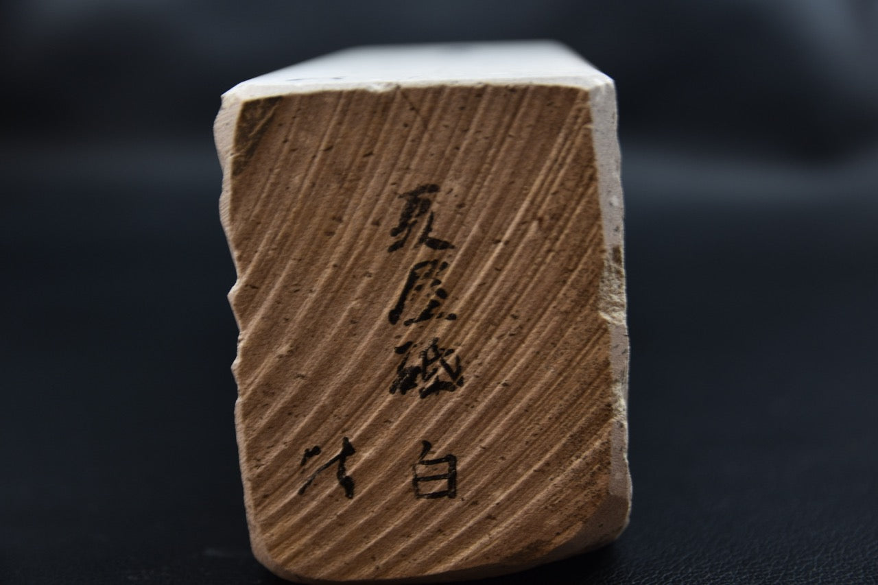 Vue de l’extrémité et des inscriptions de la pierre naturelle Natsuya blanche pour couteau japonais.
