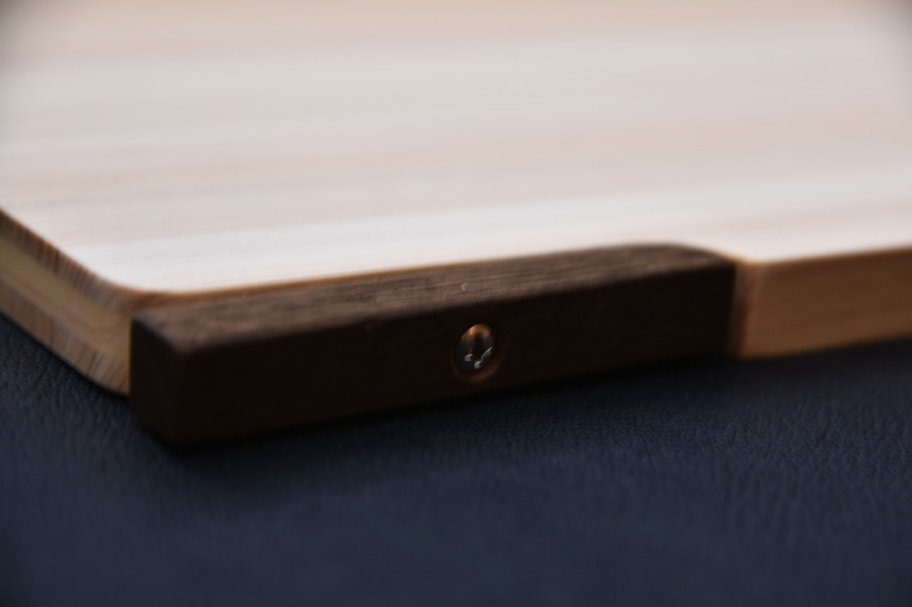 Zoom sur le pied rotatif en bois de rose fixé à la planche à découper japonaise en hinoki.