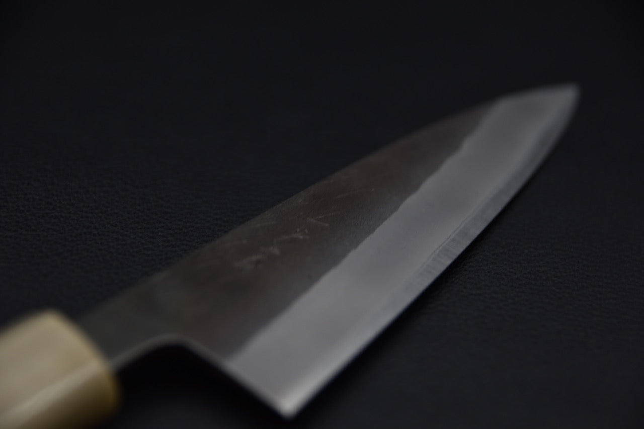 Vue rapprochée du tranchant d’un couteau japonais Petty Hitohira en acier carbone Aogami #2, finition brute de forge