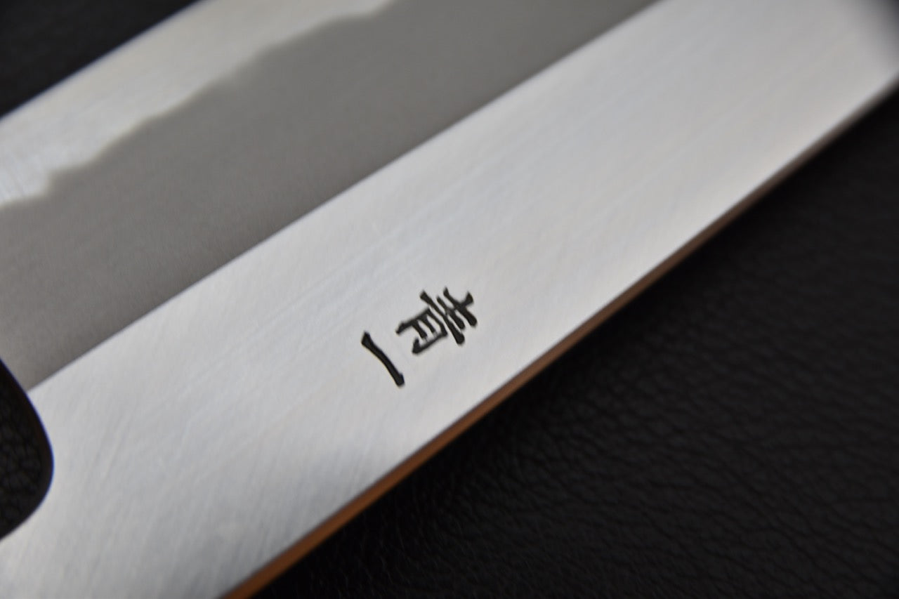Gros plan sur un Kanji japonais gravé sur un gyuto 210mm en acier carbone