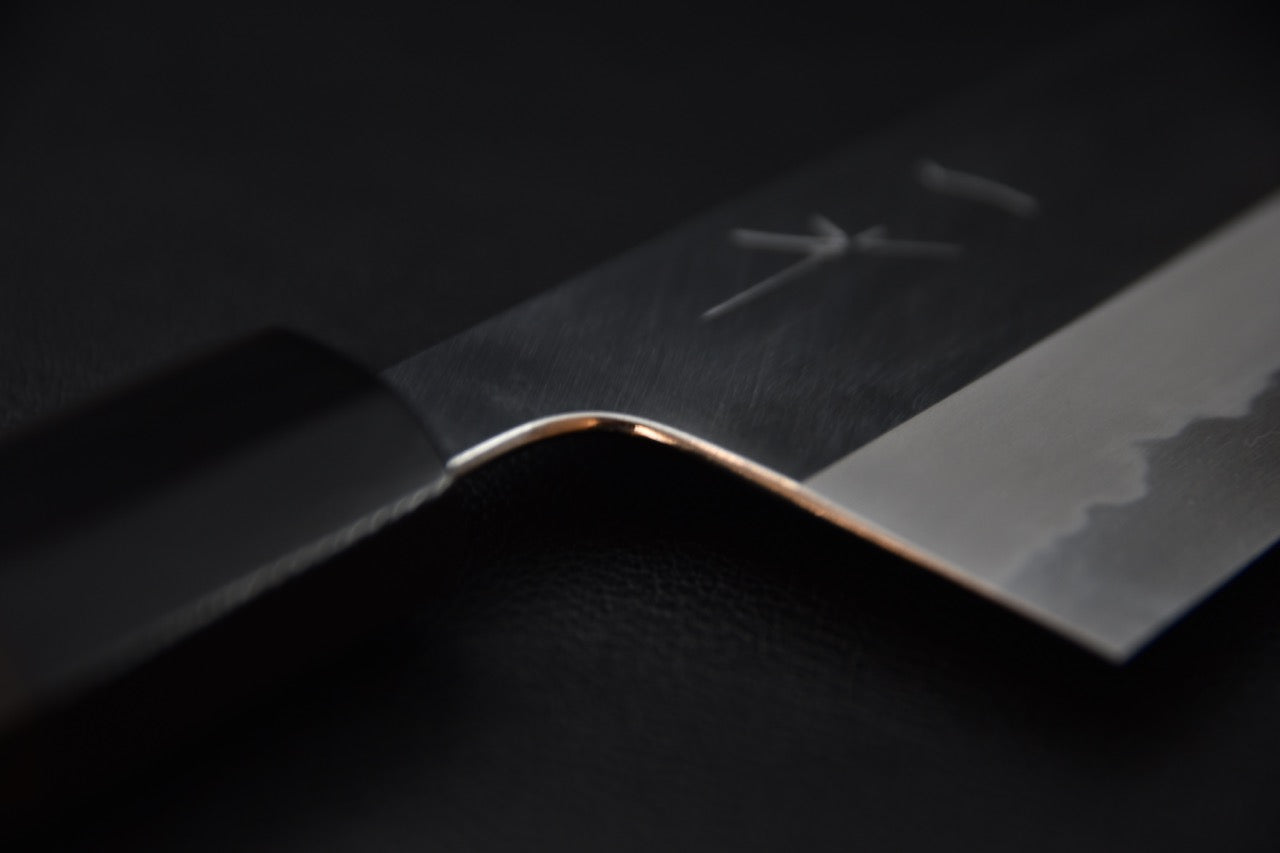 Gros plan sur la lame polie d'un couteau japonais avec manche en ébène