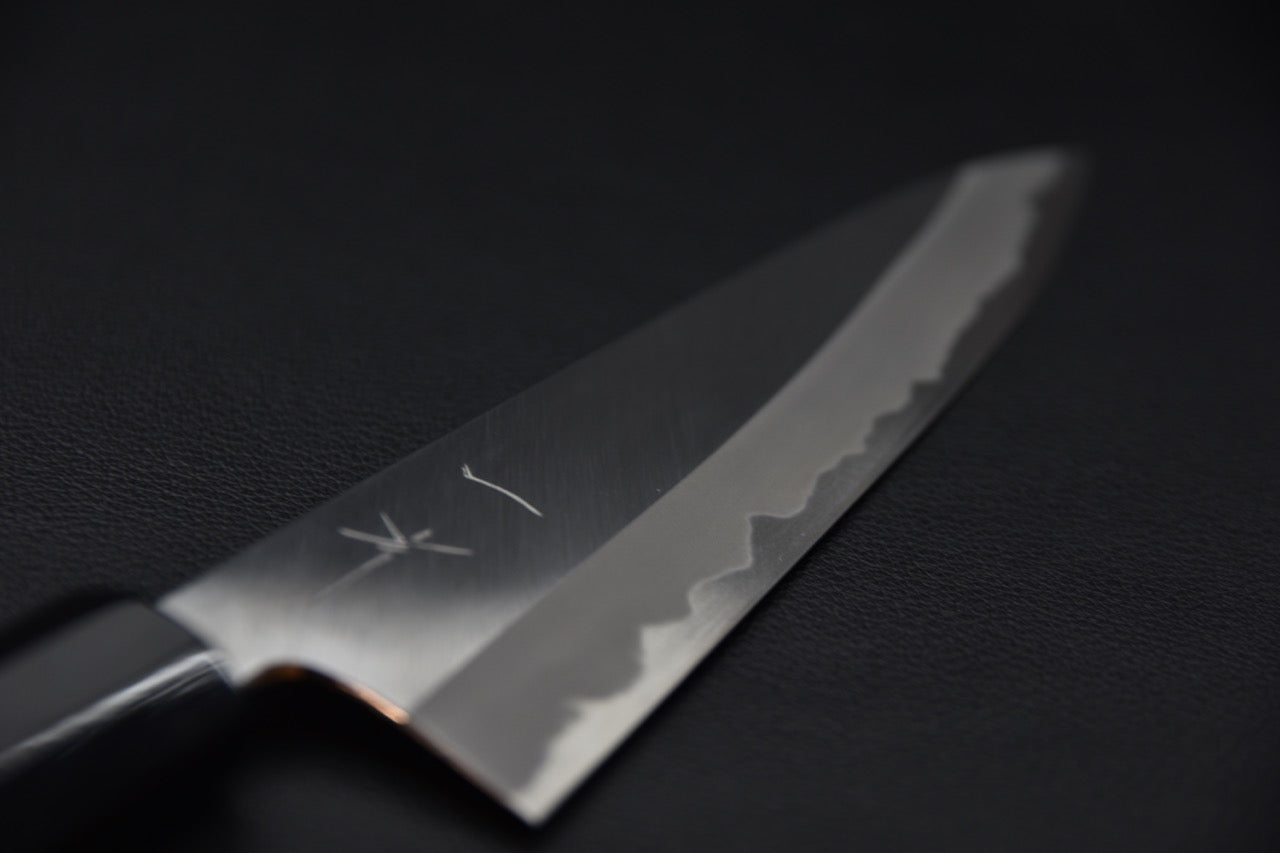 Gros plan sur la ligne de trempe Migaki d’un couteau japonais haut de gamme.