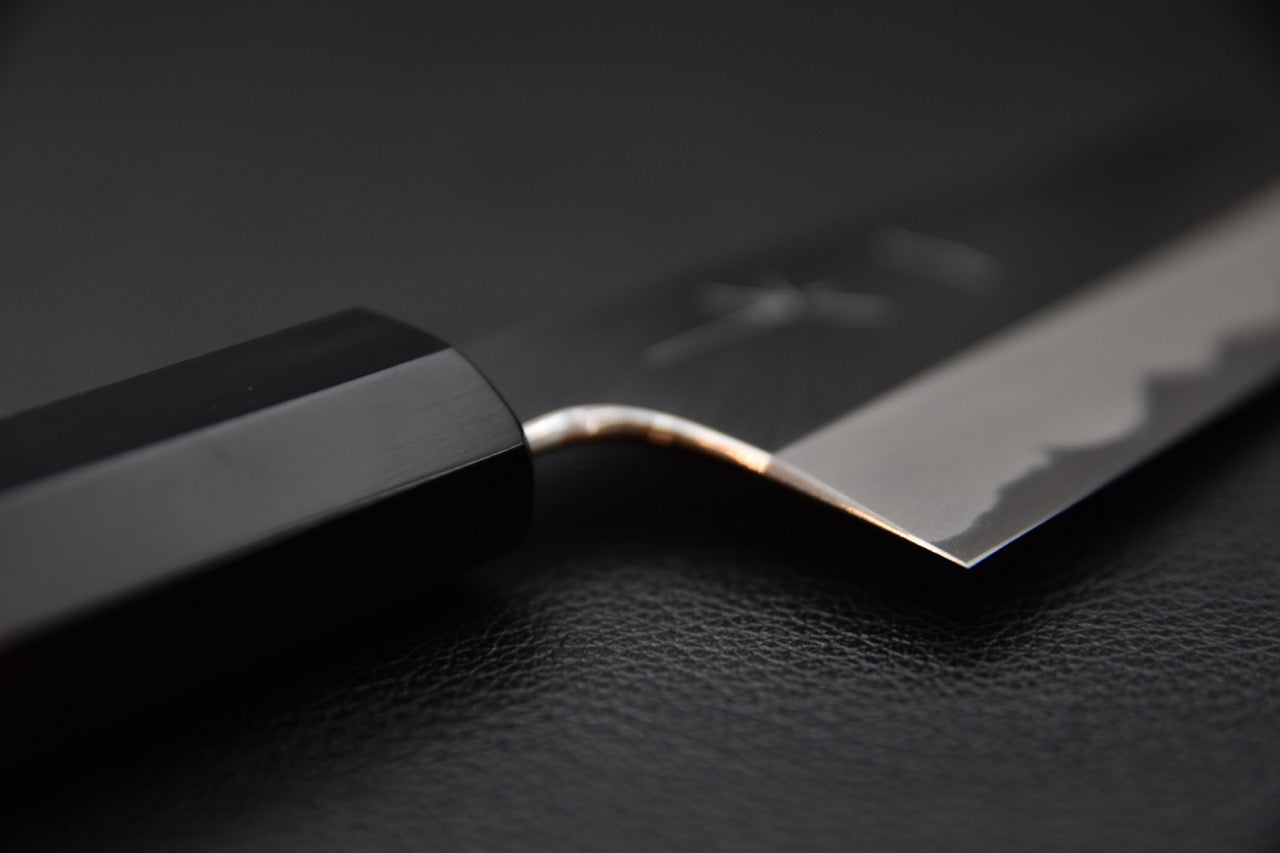 Jonction entre la lame et le manche, mettant en évidence le travail artisanal.