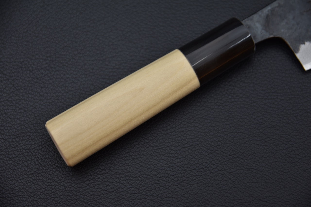 Gros plan sur le manche en bois de Ho et col foncé en résine.