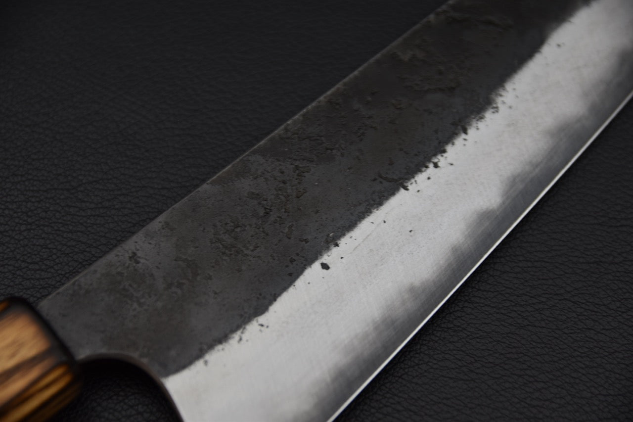 Couteau japonais Gyuto Kaizen x Stay Sharp, détail du biseau poli et de la finition kurouchi brute de forge.