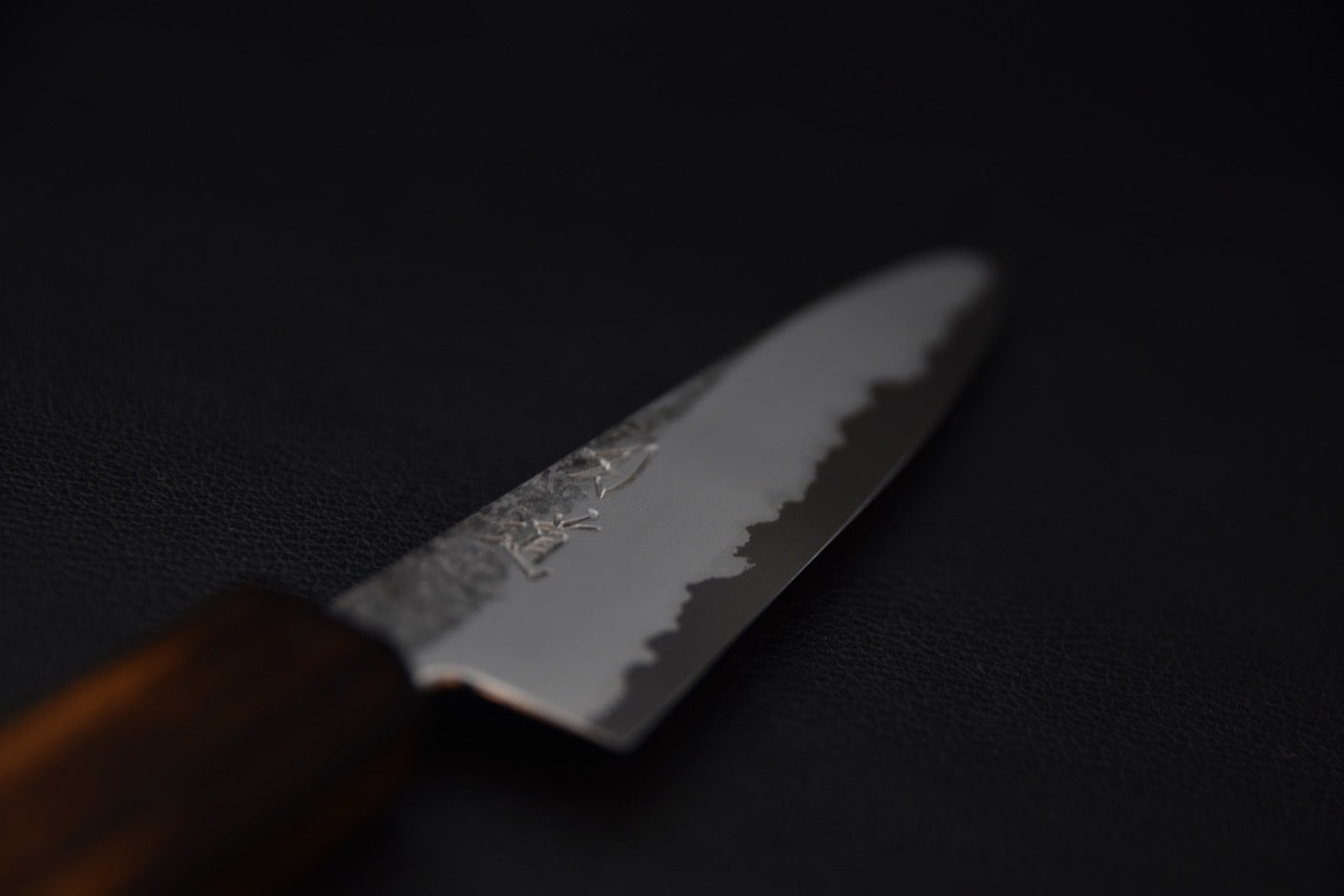 Gros plan sur la lame du couteau japonais Petty montrant la gravure et la finition nuageuse.