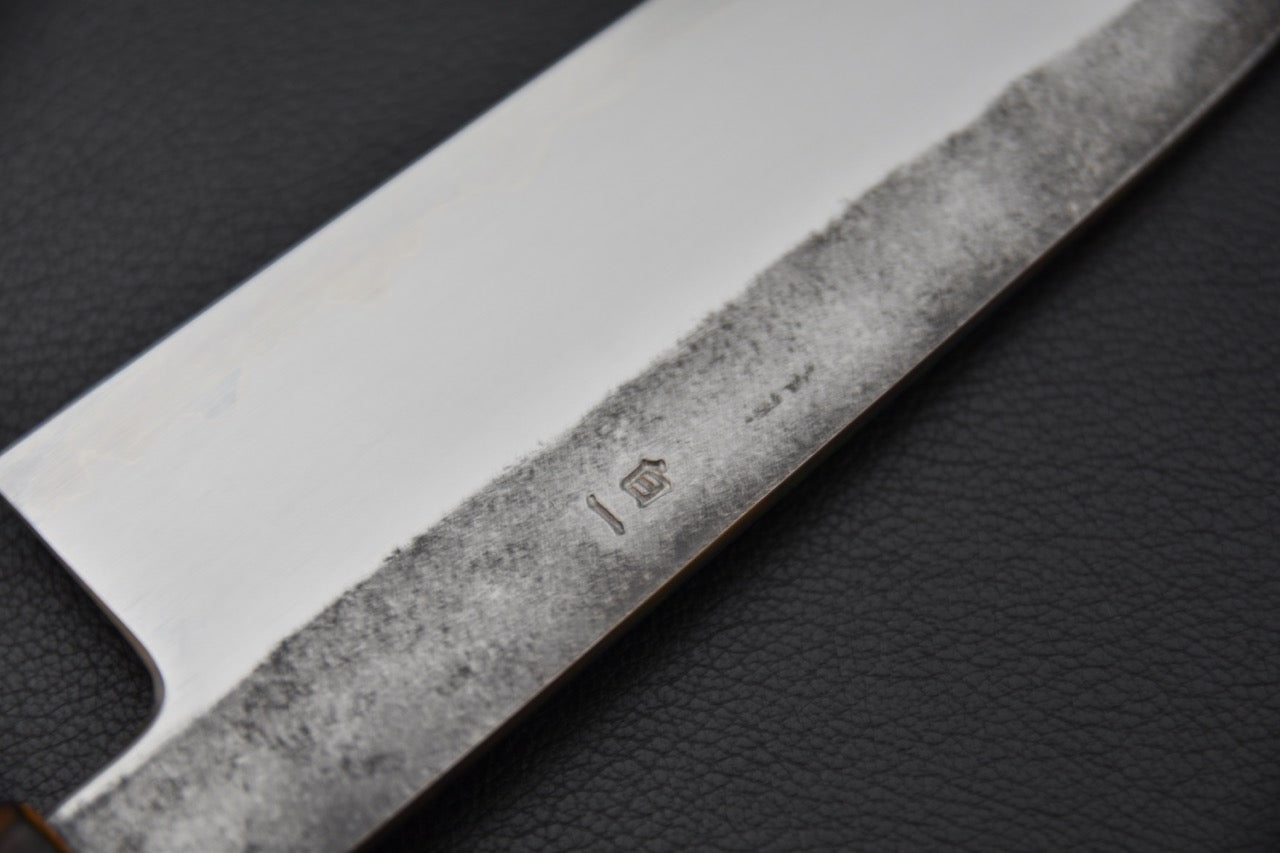 Détail du manche en bois naturel d’un couteau japonais Santoku artisanal.