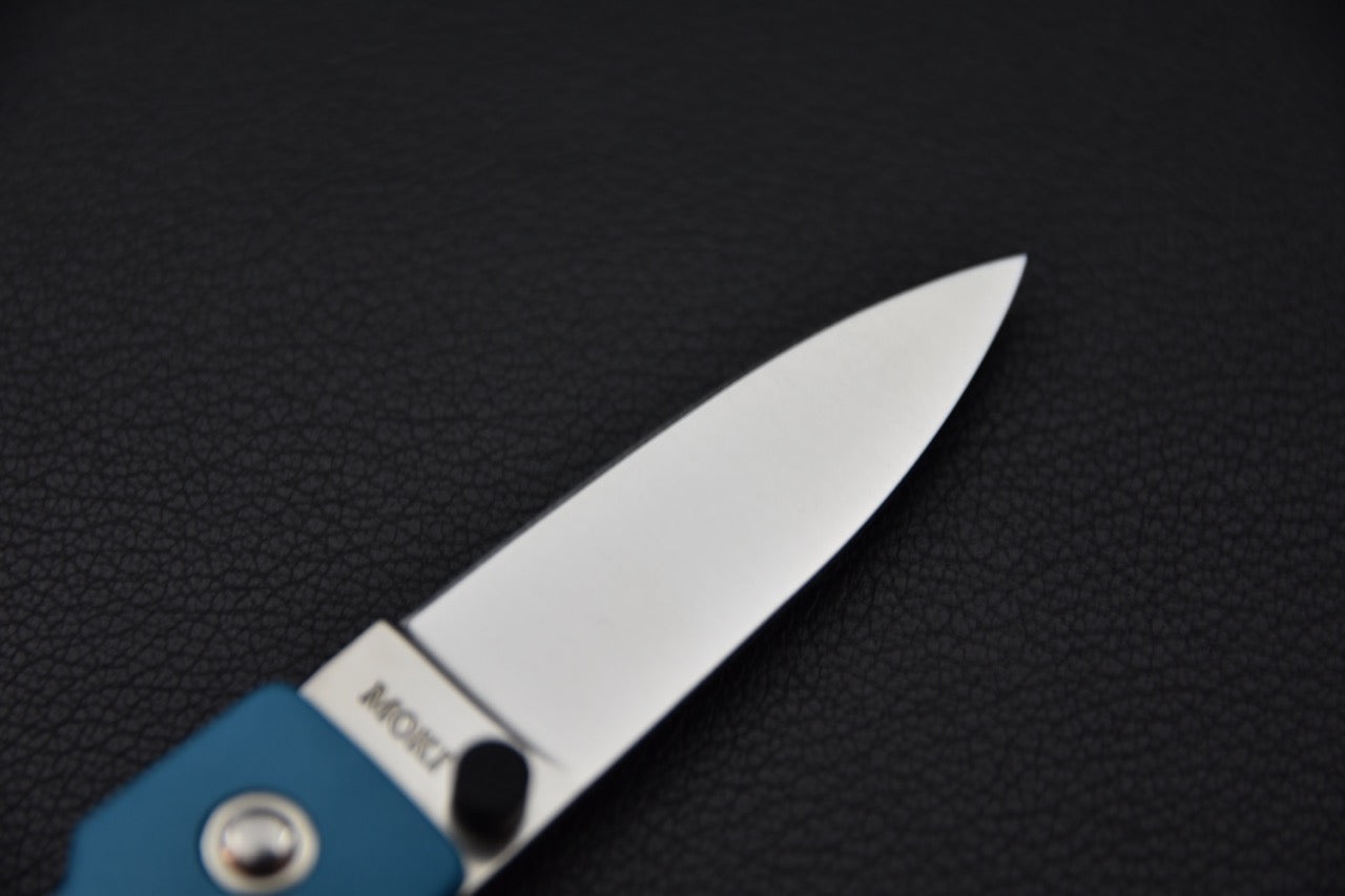 Gros plan sur la pointe de la lame du MOKI Coupe, finition polie et forme symétrique.