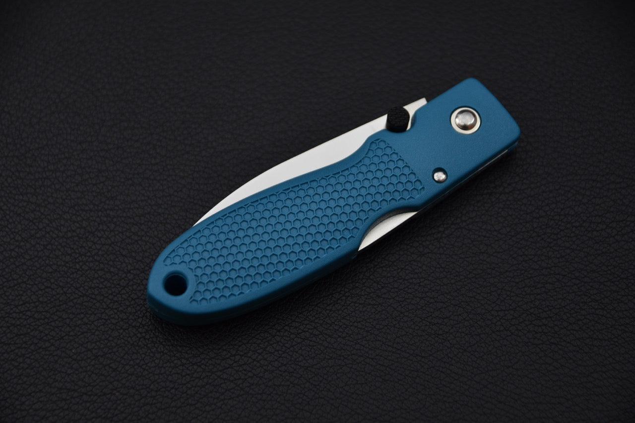 Couteau MOKI Coupe plié, manche Grilon bleu-gris texturé visible, lame partiellement rentrée.