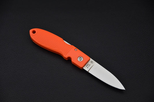 Couteau pliant MOKI Coupe ouvert sur fond noir, lame en acier inoxydable et manche orange texturé.