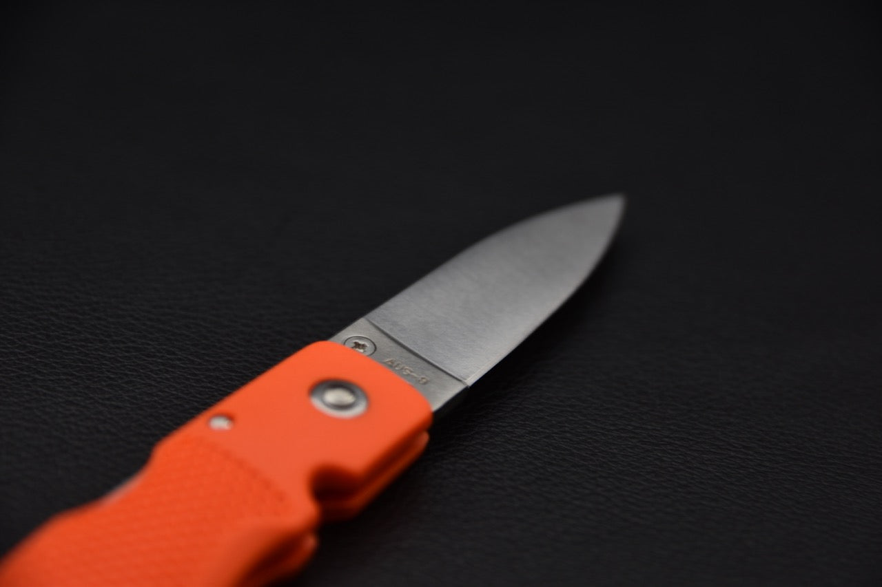 Gros plan sur la lame du couteau pliant MOKI en acier AUS-8, marquage visible.