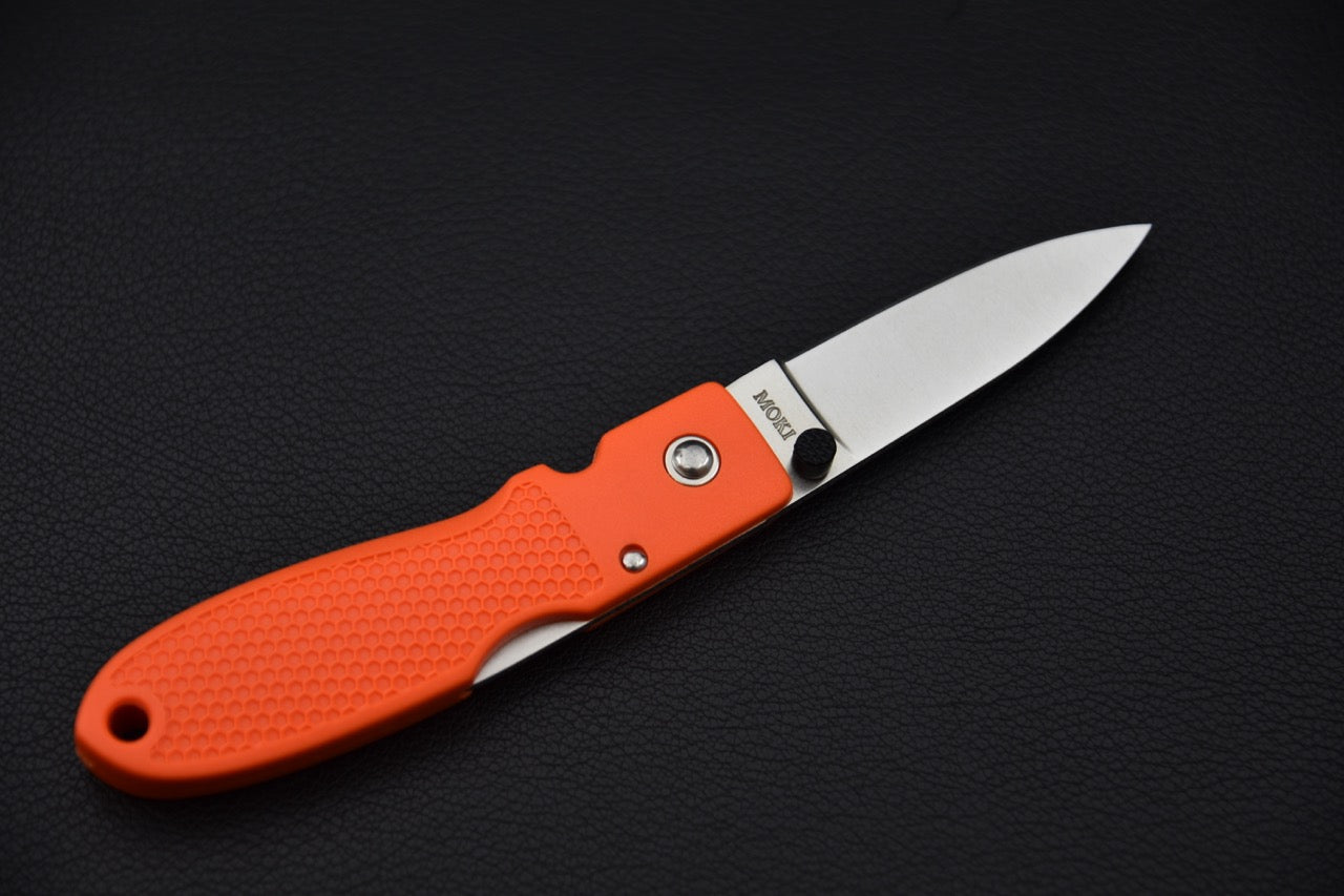 Vue latérale du couteau MOKI Coupe ouvert, montrant le manche orange vif et la lame.