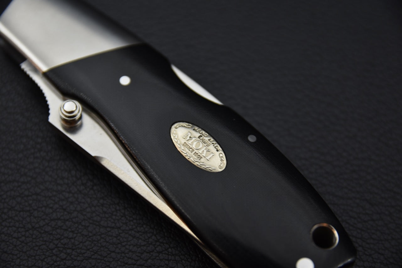 Vue rapprochée du manche en Micarta de lin du MOKI Kingfisher et médaillon gravé