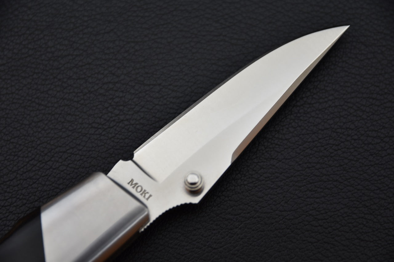 Gros plan sur l’inscription “MOKI” gravée à la base de la lame