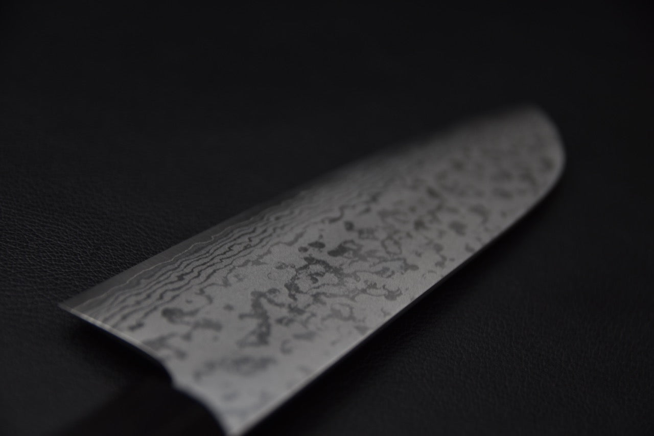 Gros plan sur le motif damassé d’un couteau japonais santoku en acier VG7