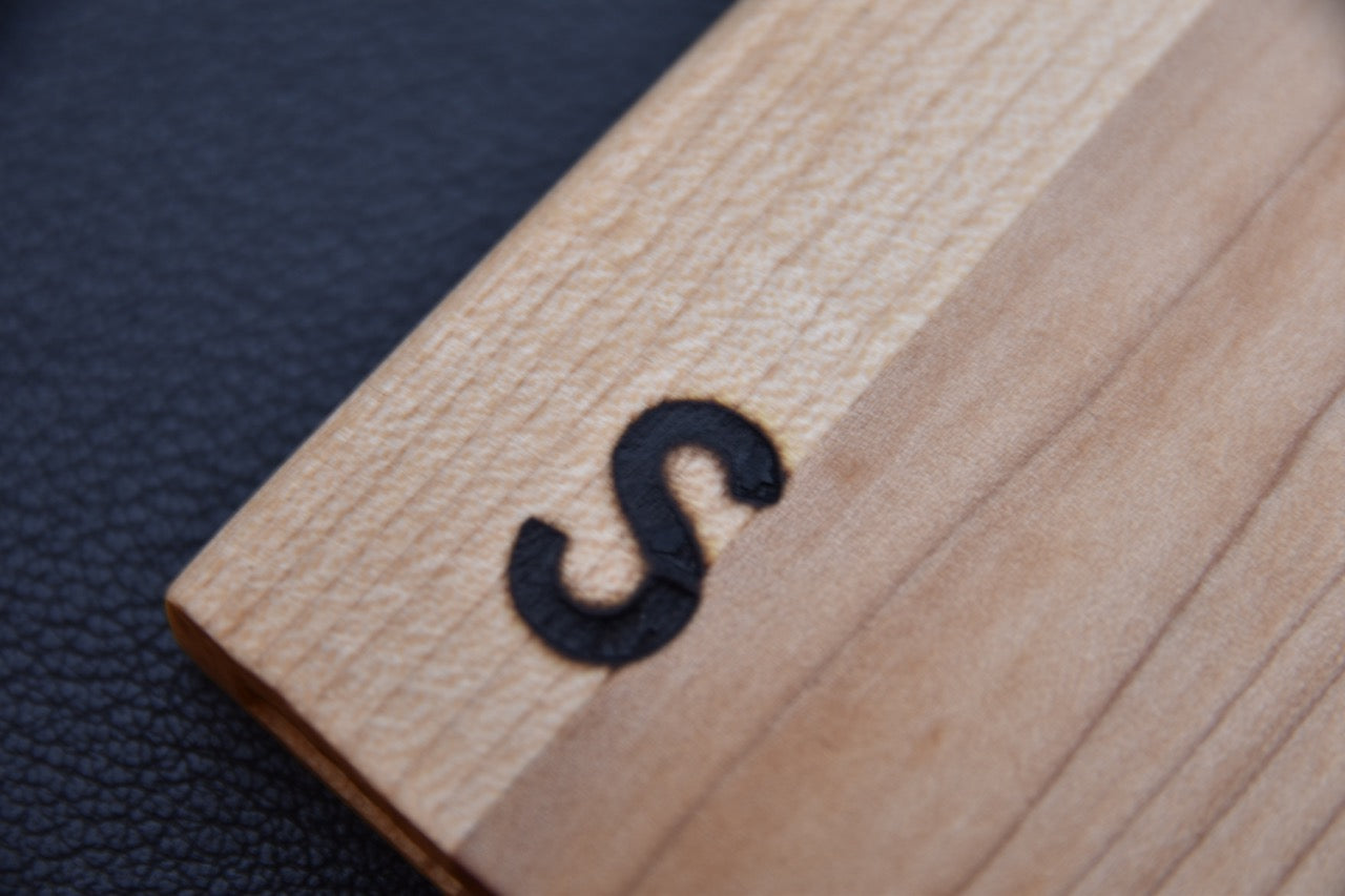 Vue rapprochée de la gravure "S" sur un saya pour couteau japonais.