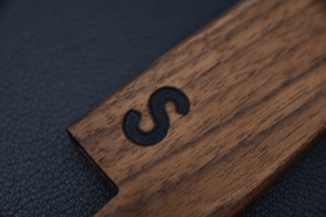 Gros plan du logo gravé sur la saya en bois Maku pour couteau japonais.